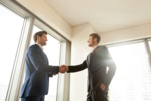 Smiling executive director handshaking with business partner in office, thanking company manager for good work, congratulating employee with promotion. Successful negotiation, strong partnership